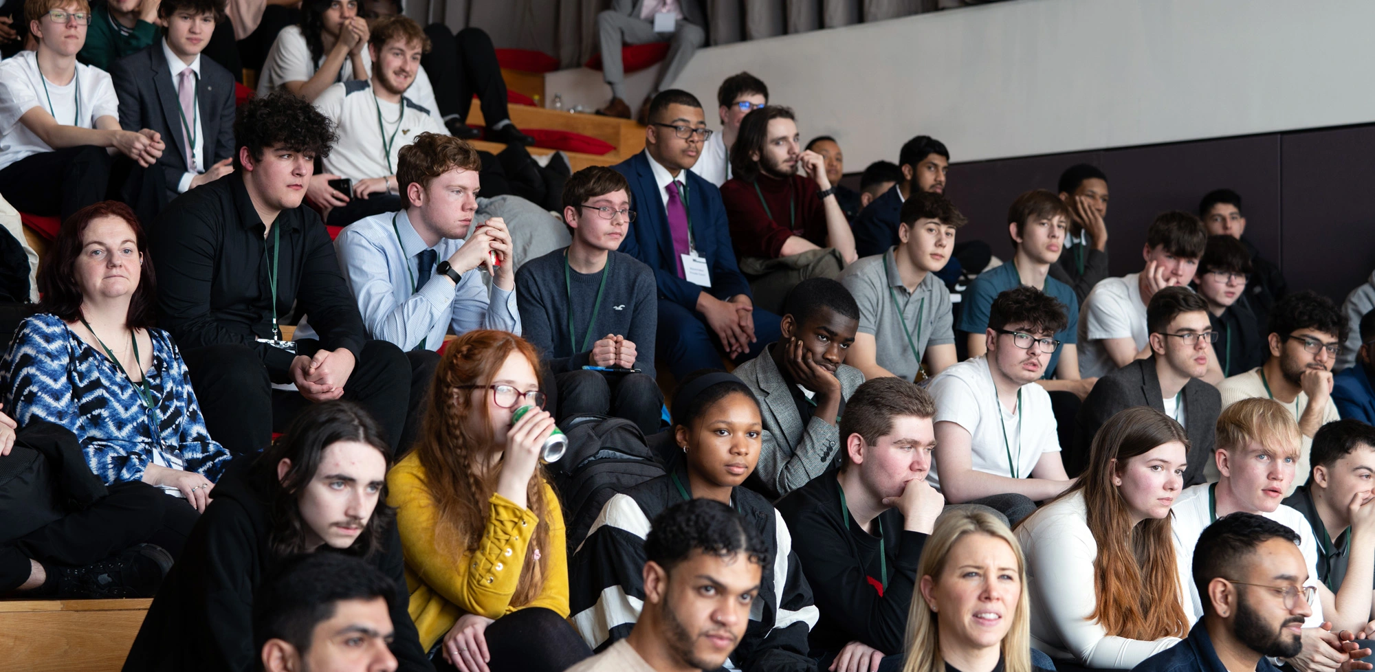 An audience of students sit in a tiered auditorium listening to a speaker