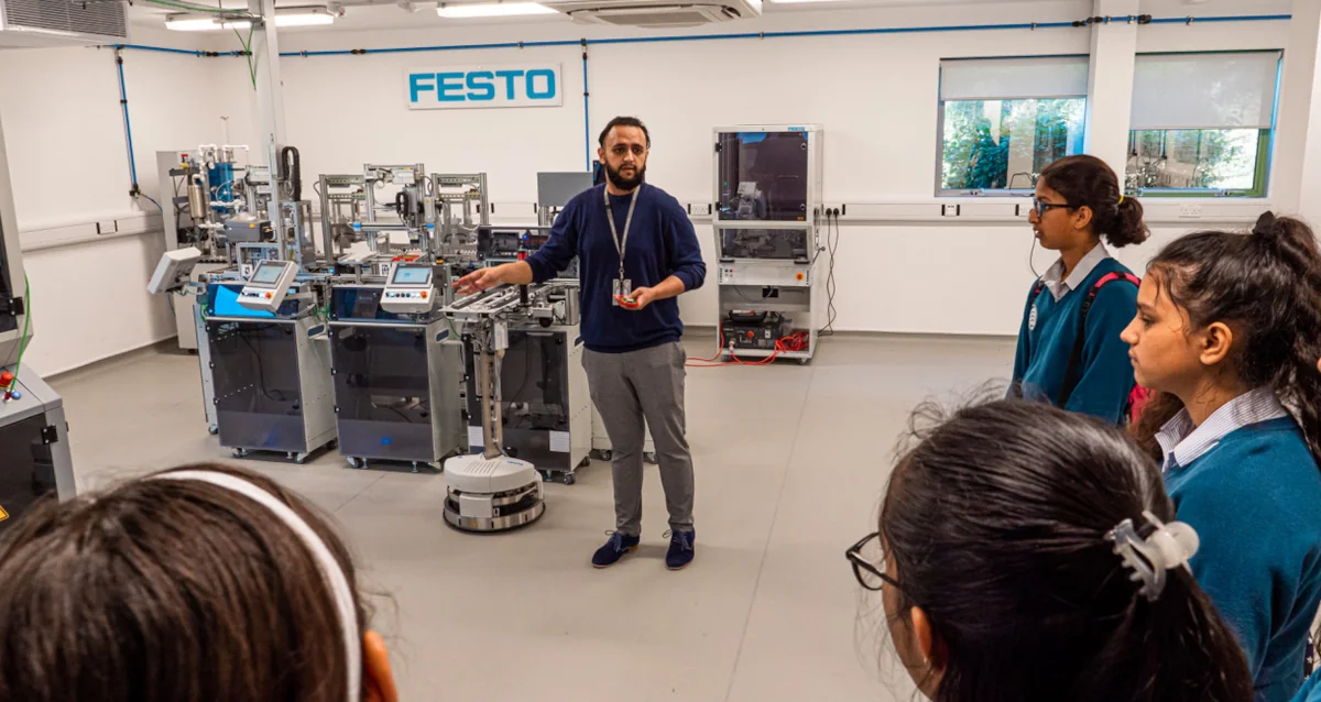 Student listening to an employee at BAE Systems in a laboratory enviornment